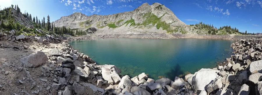 A turquoise glacial lake ringed by boulders near the head of the canyon.