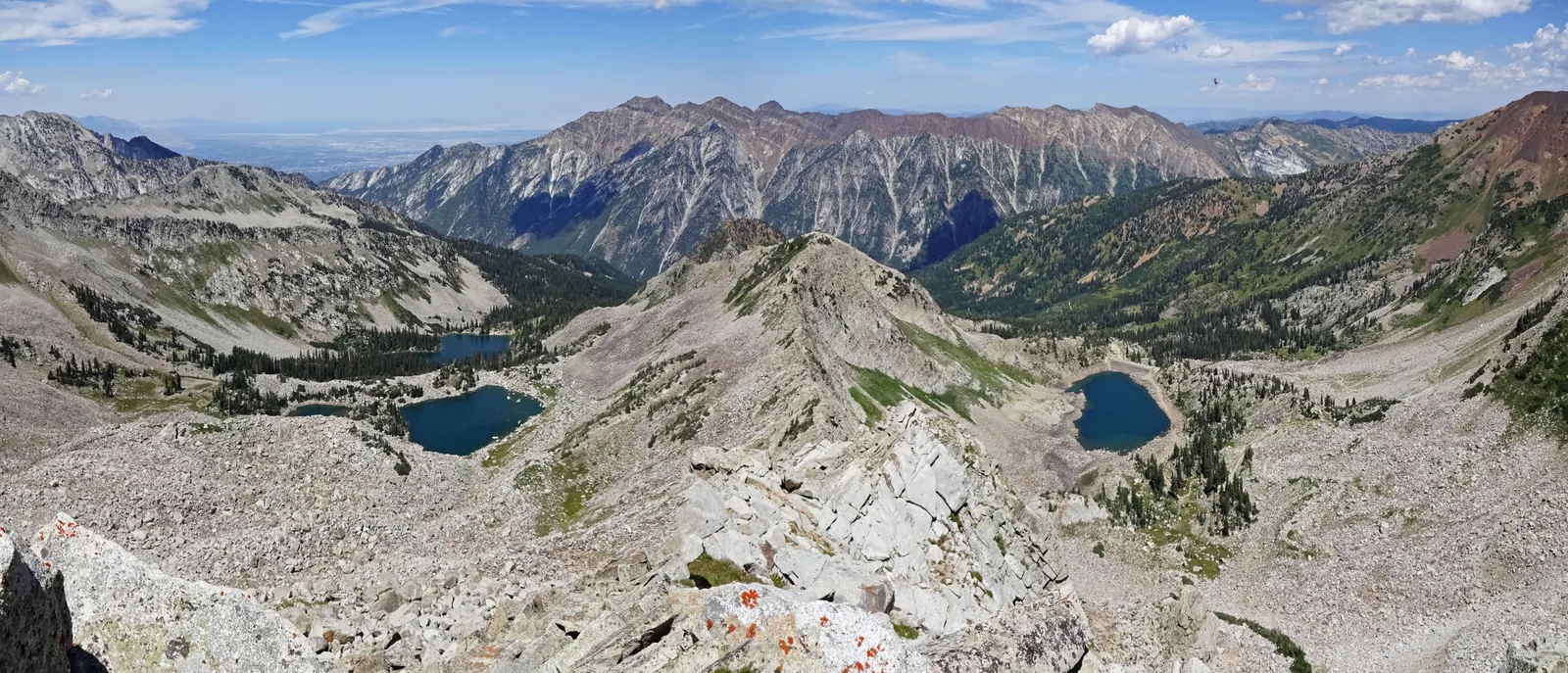 The alpine basin above Little Cottonwood Canyon in summer, granite ridges holding small lakes.