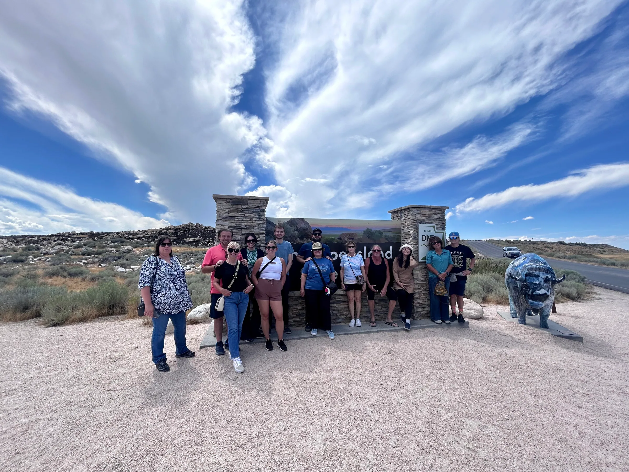 A small tour group at the Antelope Island State Park entrance sign on the causeway