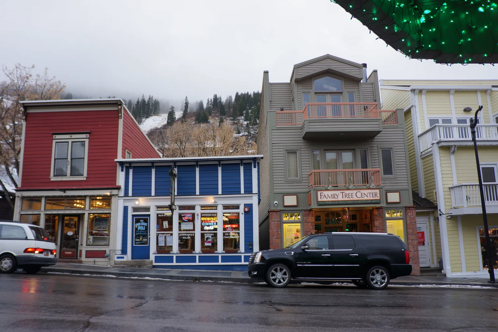 The painted timber storefronts of historic Main Street in Park City, with the ski mountain rising at the end of the road.