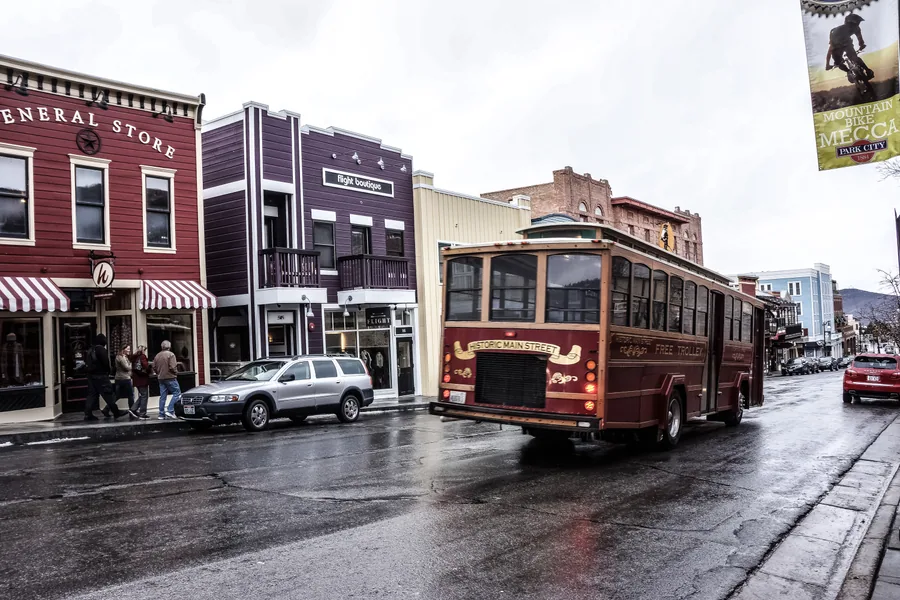 A red trolley bus running past the old general store on Park City's Main Street.