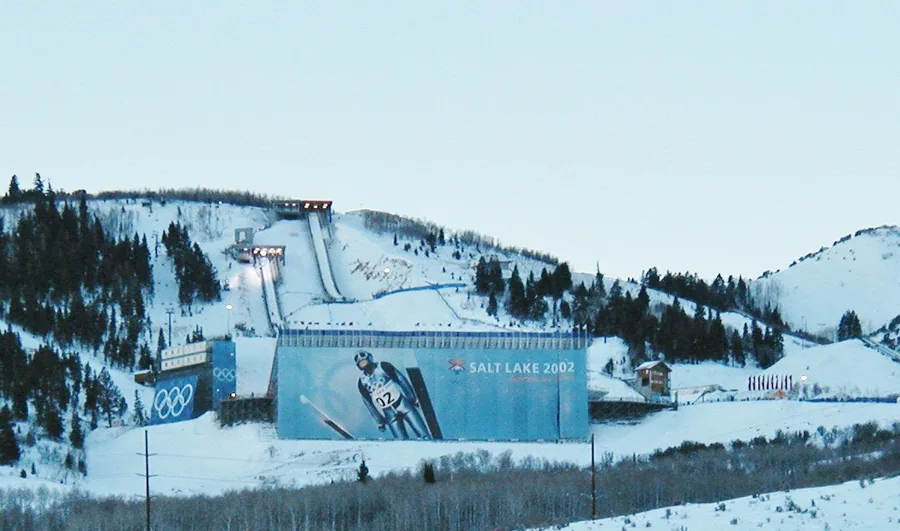 The ski jump landing hill at Utah Olympic Park under snow, with the Salt Lake 2002 banner across it